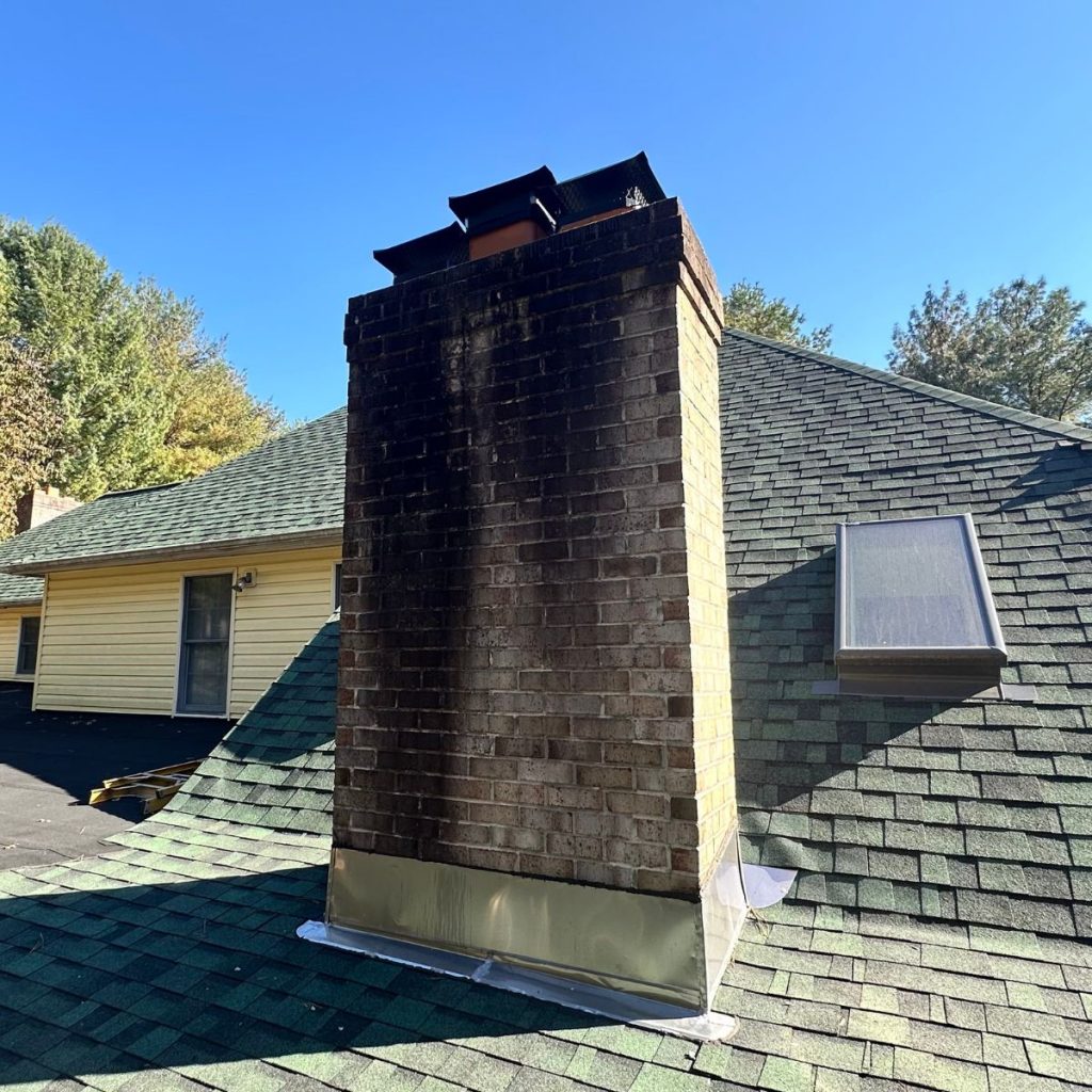 Dirty brick chimney with heavy soot stains on exterior wall.