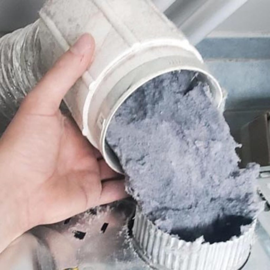 Hand holding dryer vent pipe packed with thick lint buildup