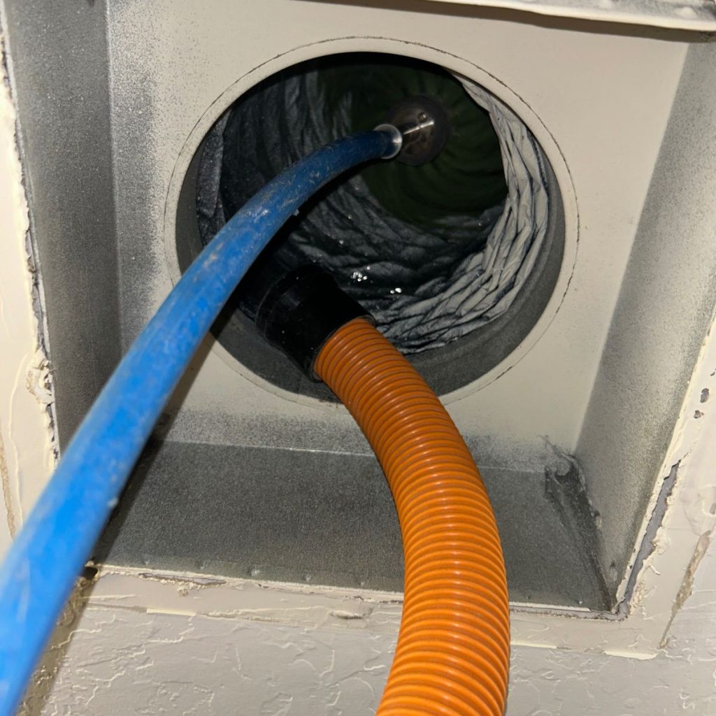Dryer vent duct being cleaned with professional vacuum hoses