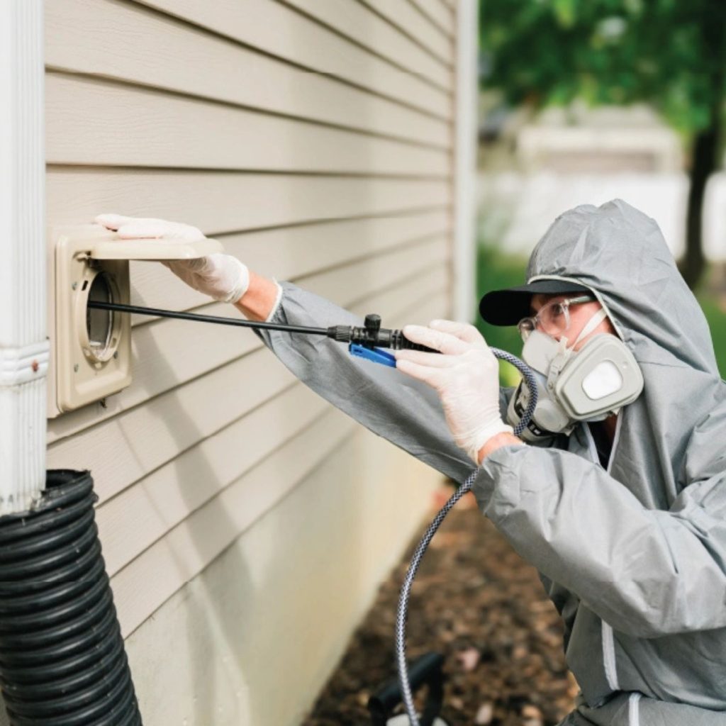 Technician in protective gear cleaning outdoor dryer vent