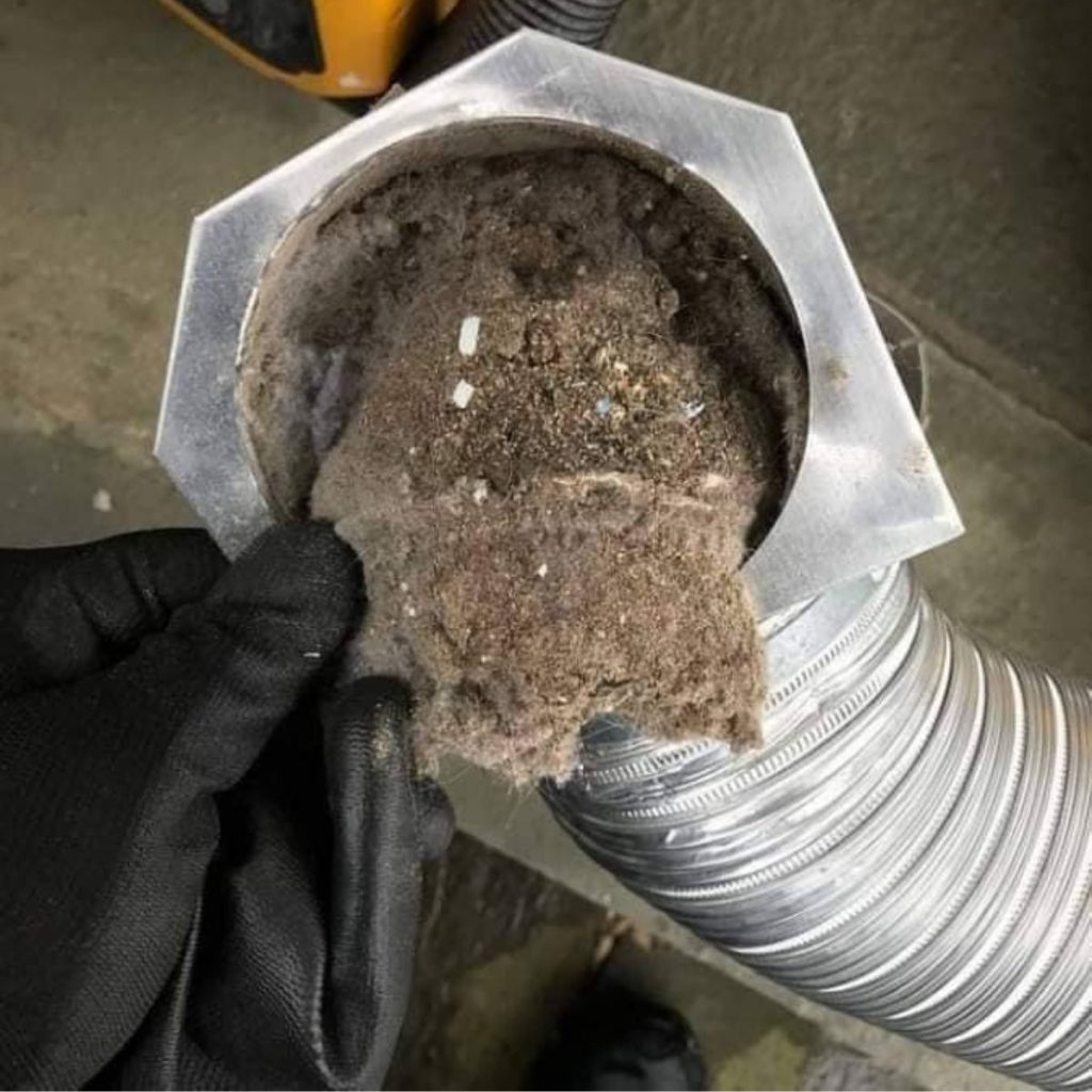 Hand removing thick lint clog from inside dryer vent duct