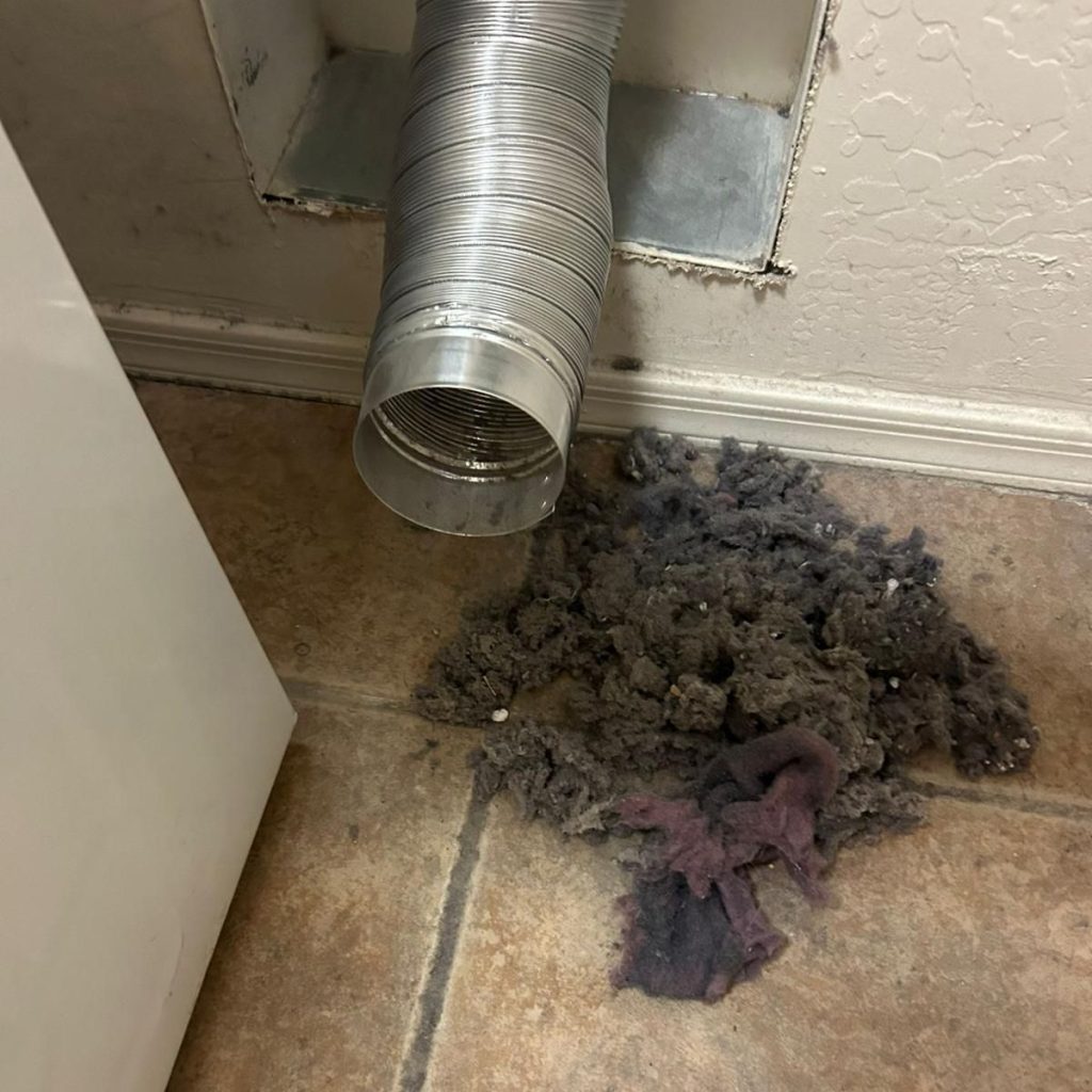 Dryer vent with lint buildup removed from duct on tile floor