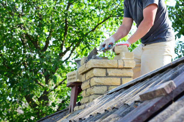 Worker repairing a brick chimney on a house roof.