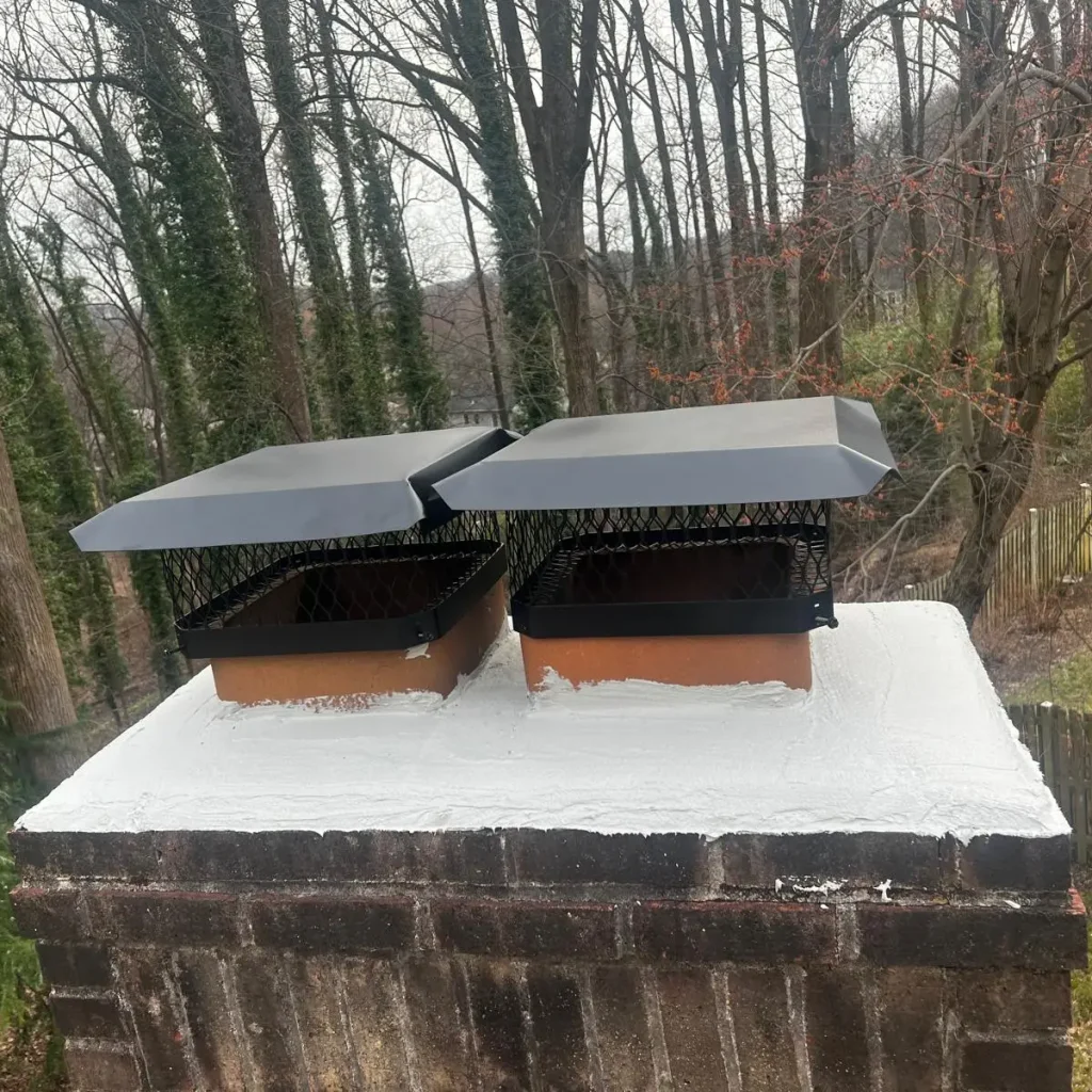 Chimney with two new metal caps installed on freshly sealed crown.