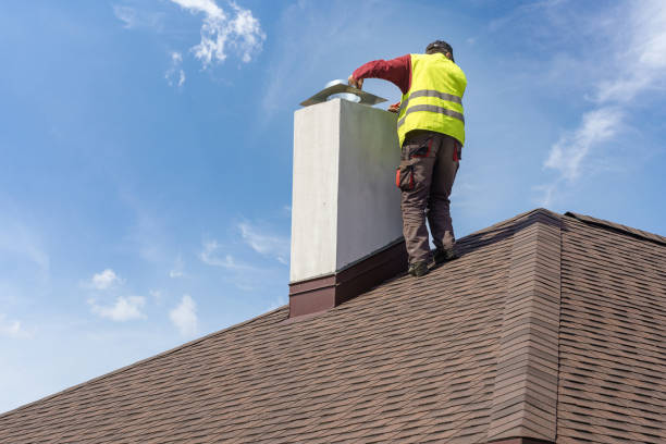 Technician installing metal cap on stucco chimney for weather protection.
